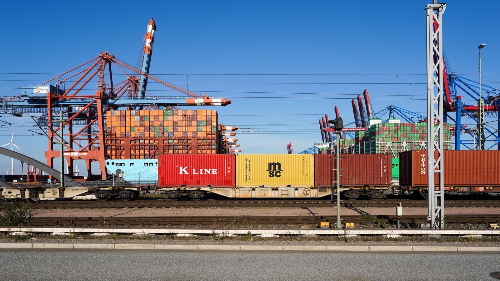 A container train passing cranes at a port