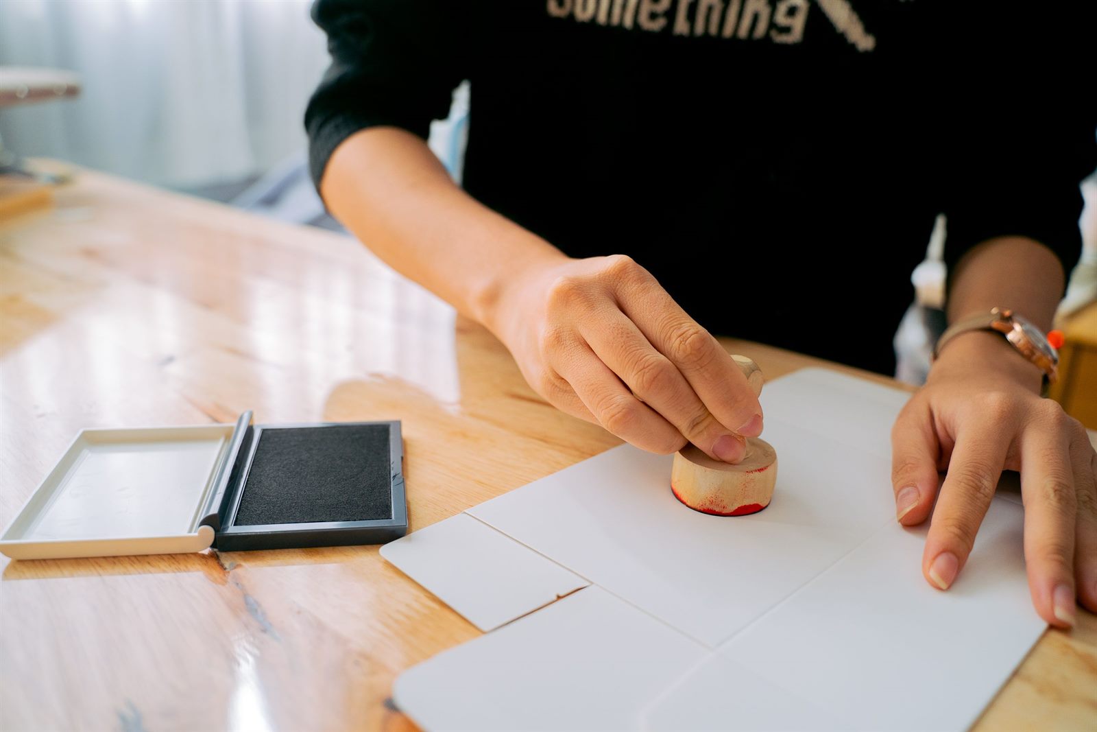 Hands stamping a document on a desk