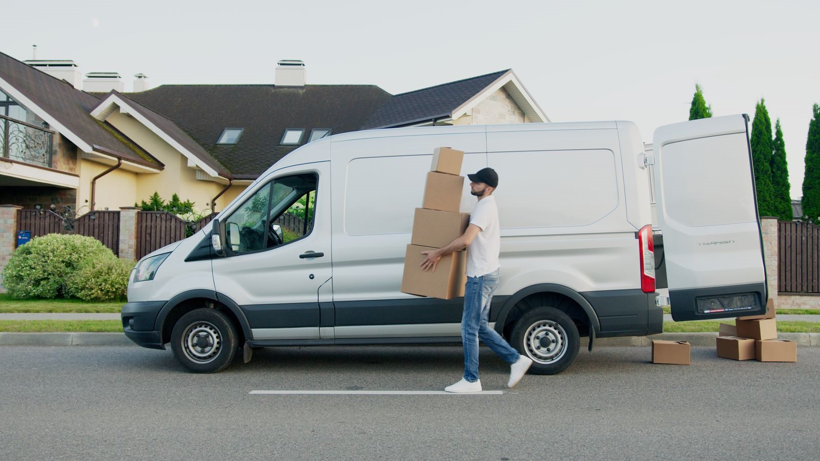 A man carrying boxes from a van to a house