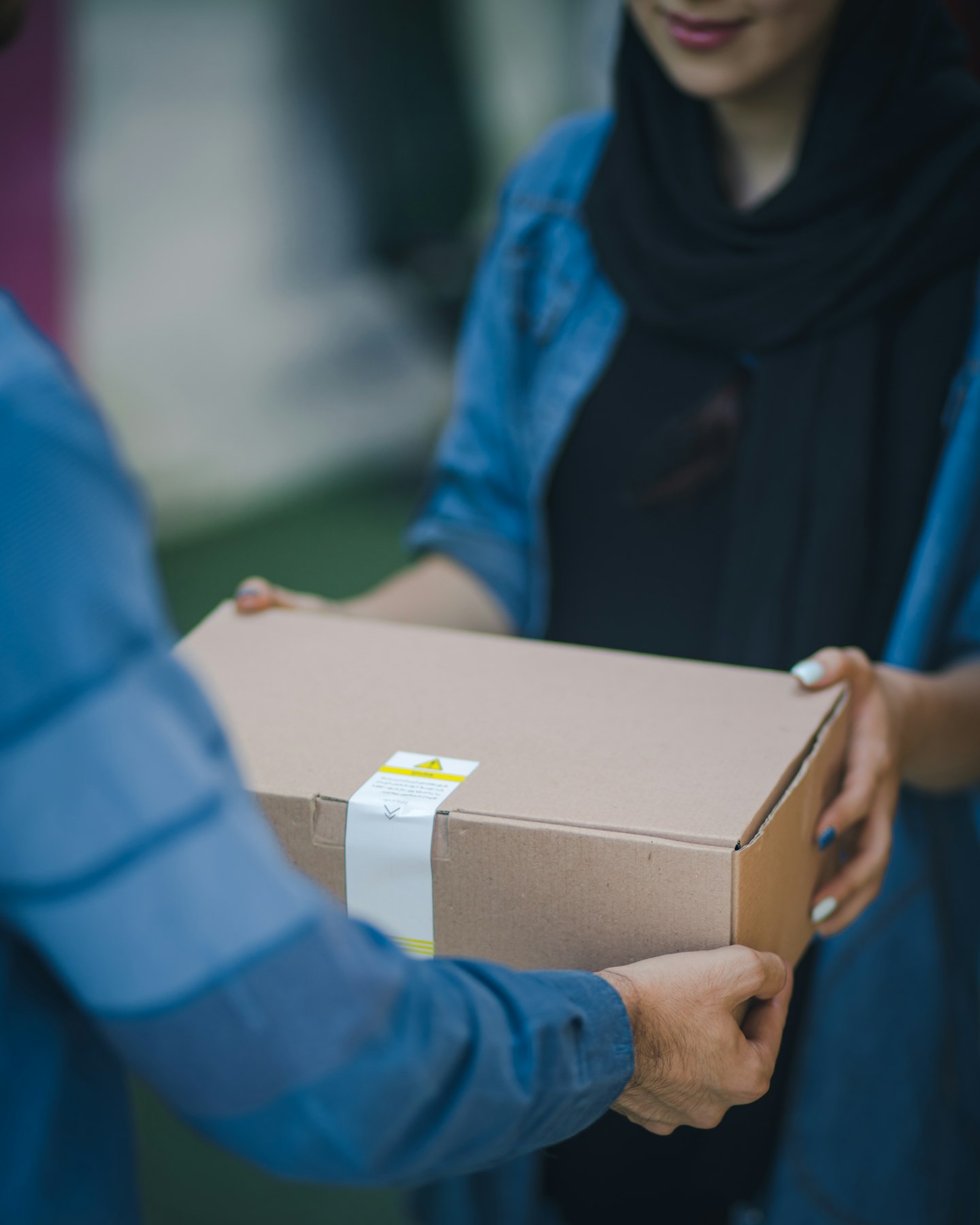 A cardboard box being handed to a woman at home