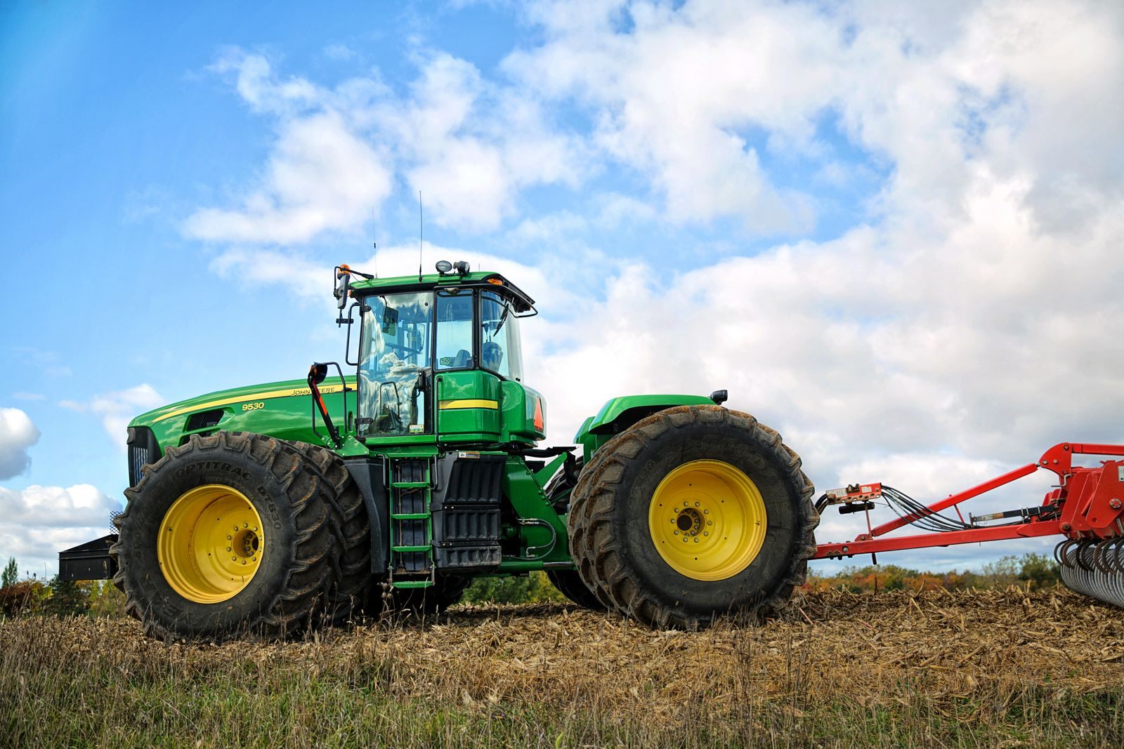 A green tractor with a tillage implement in a field