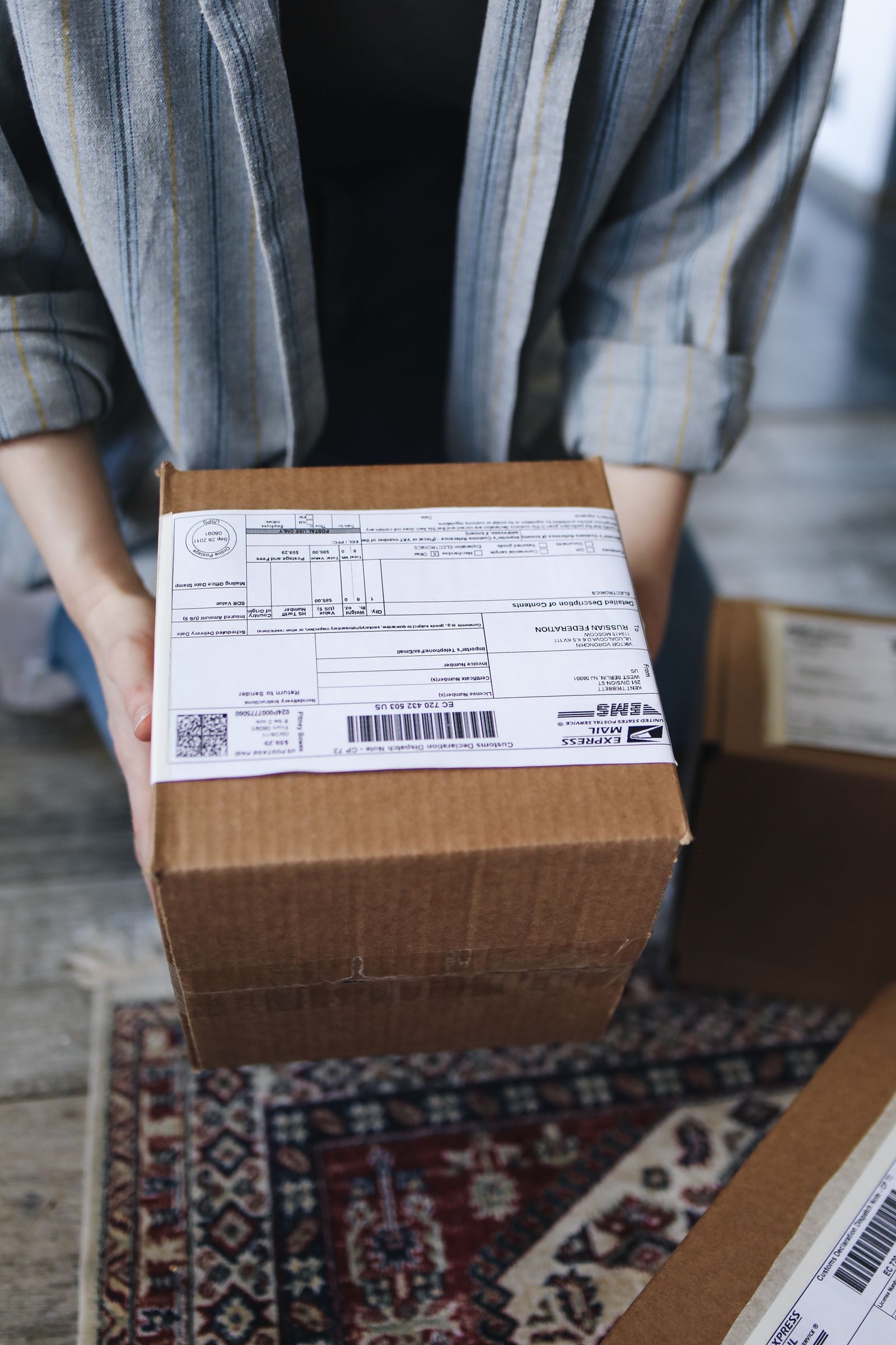 Hands holding a labelled parcel ready to send