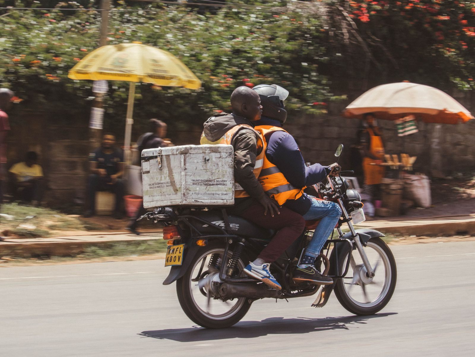 A motorbike rider carrying a box along a street in Nairobi