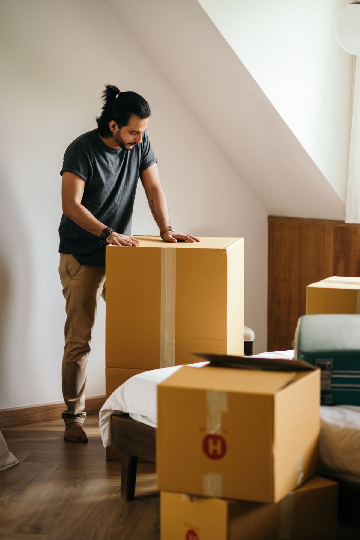 A man packing large cardboard boxes at home