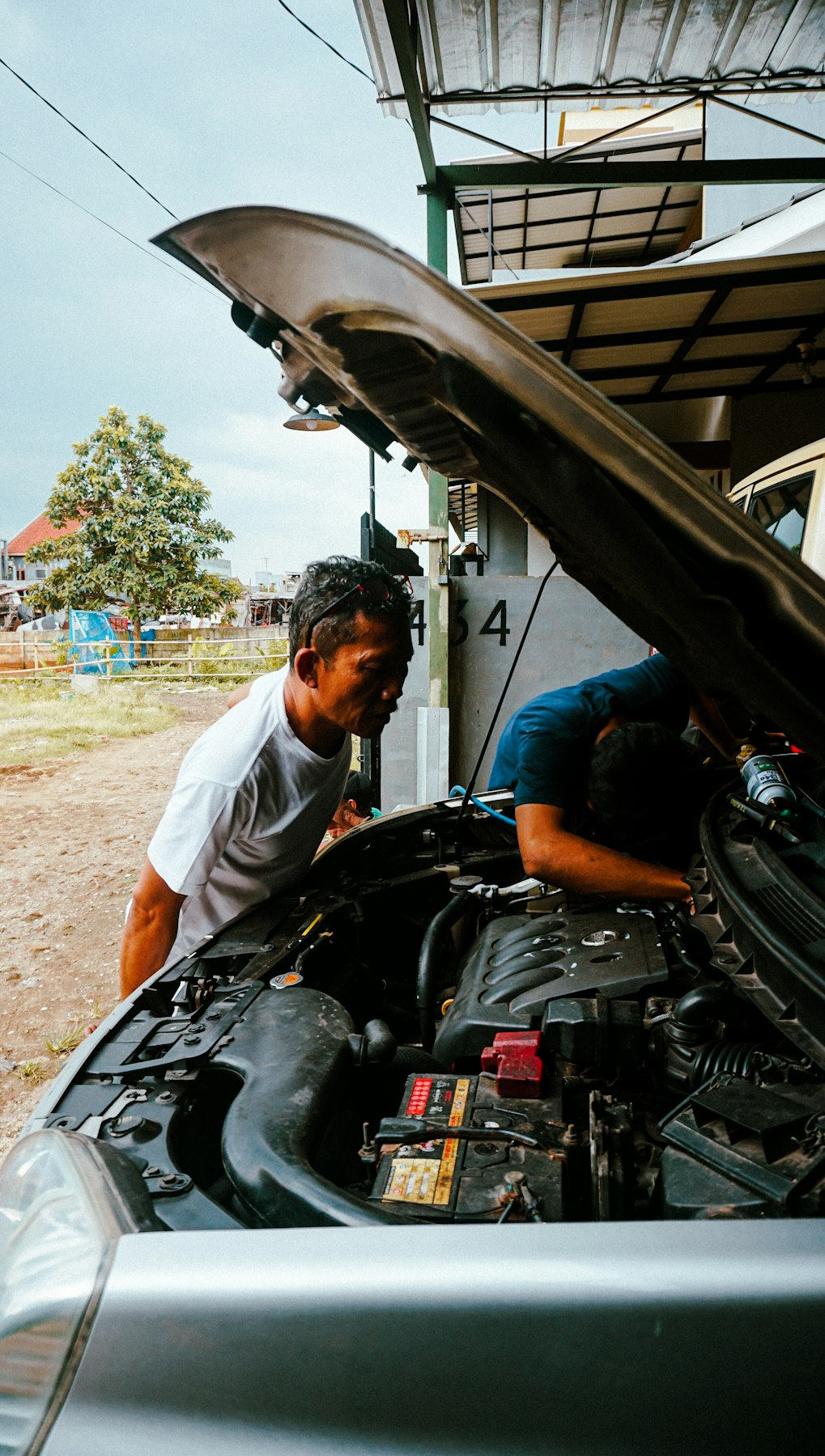 Two people checking under the bonnet of a car